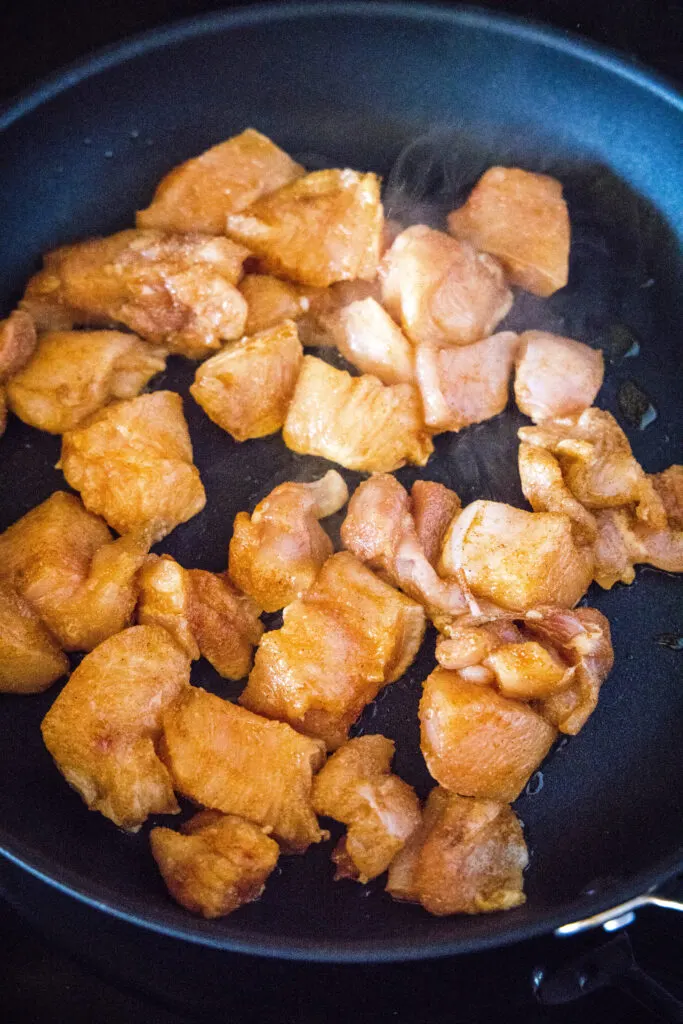 cooking chicken pieces in a skillet