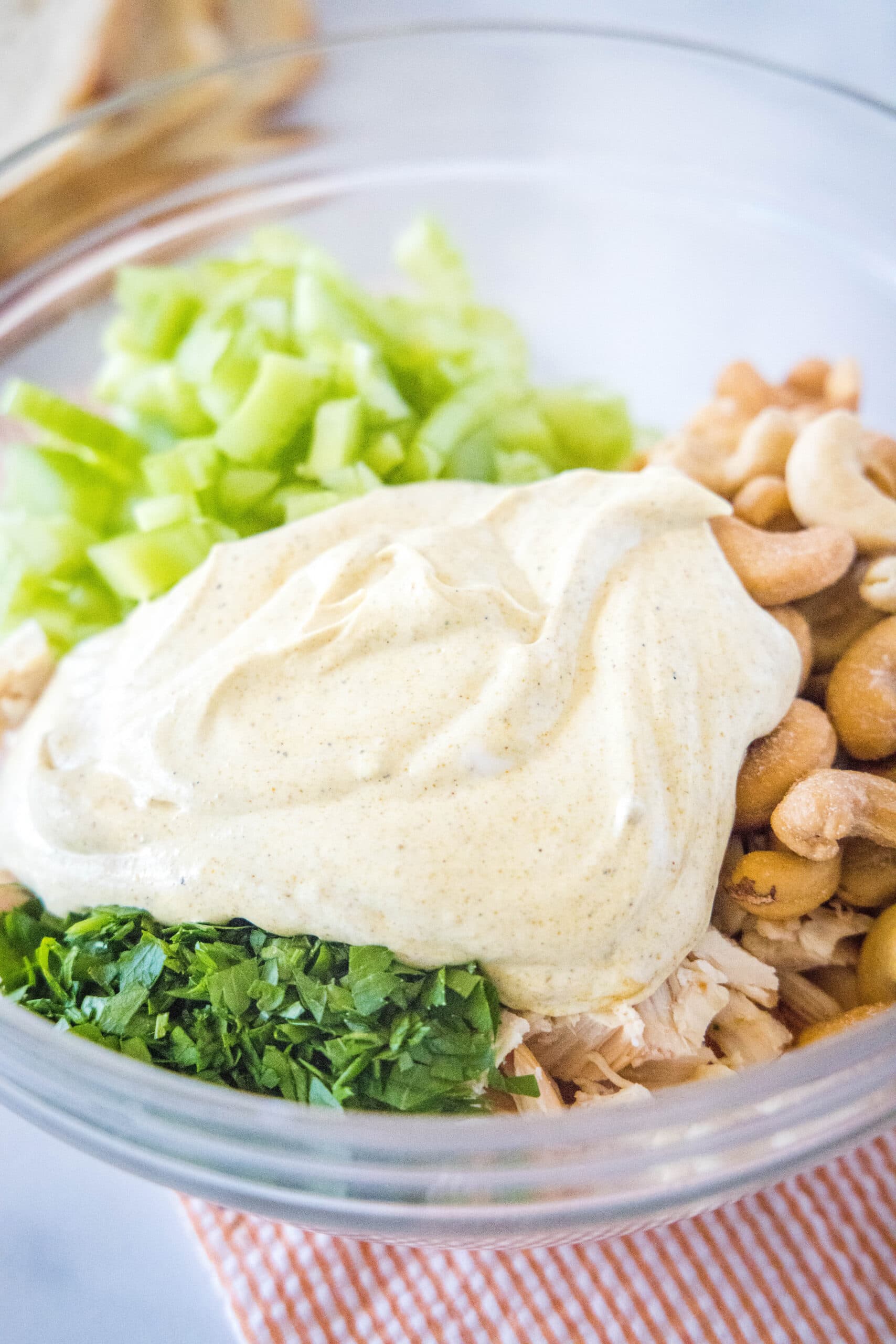 adding curry dressing over the chicken mixture in mixing bowl