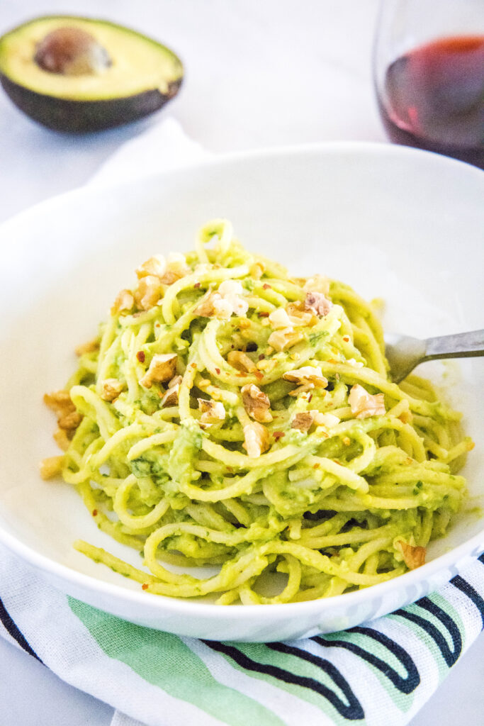 creamy avocado pasta topped with nuts