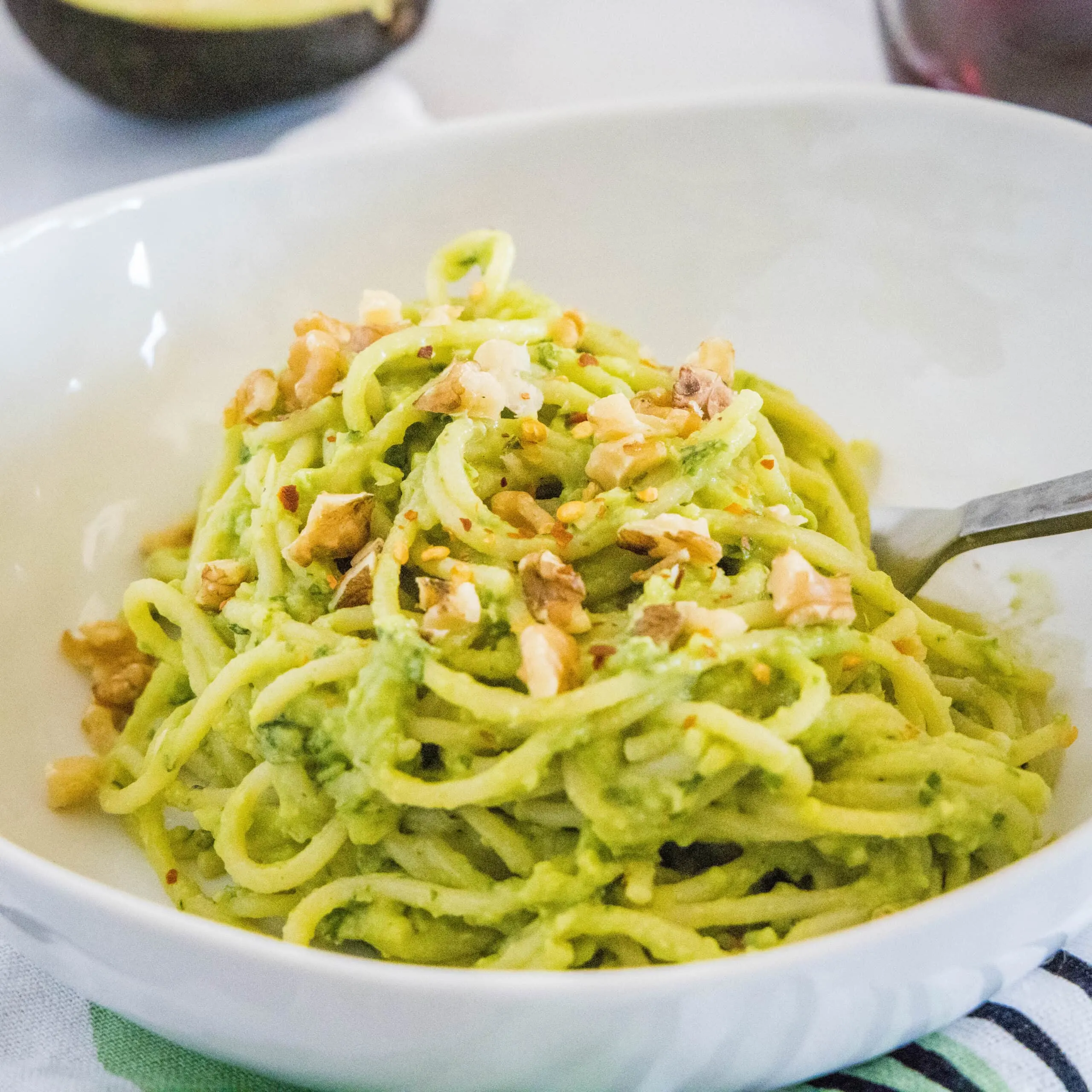 close up avocado pasta topped with walnuts