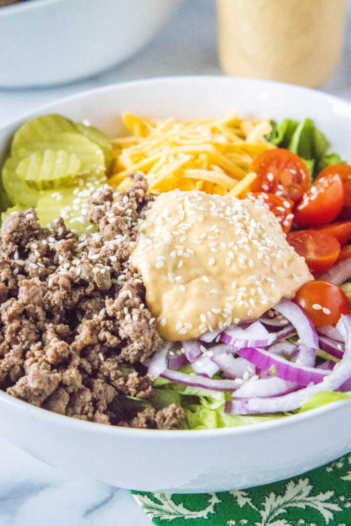 big mac salad topped with dressing and sesame seeds