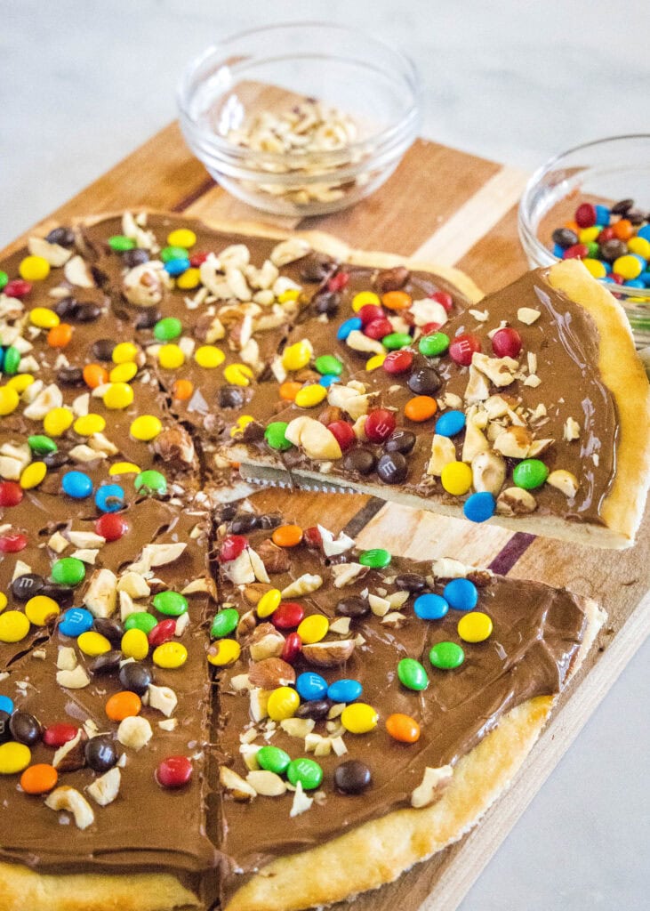 taking a slice of chocolate pizza off a cutting board