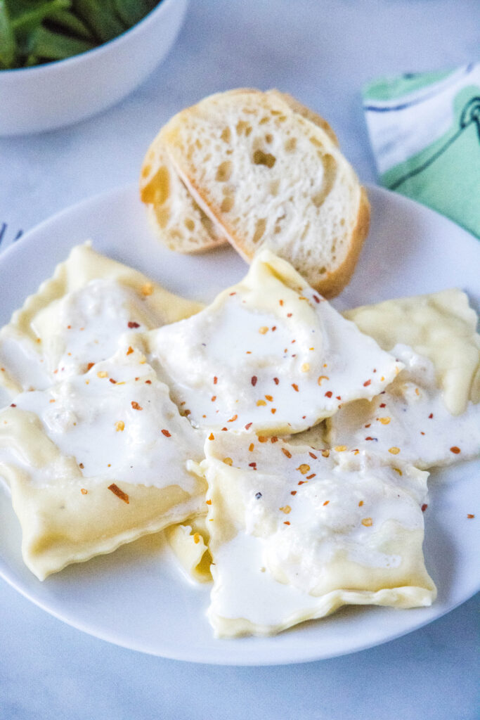 ravioli topped with garlic cream sauce on a white plate