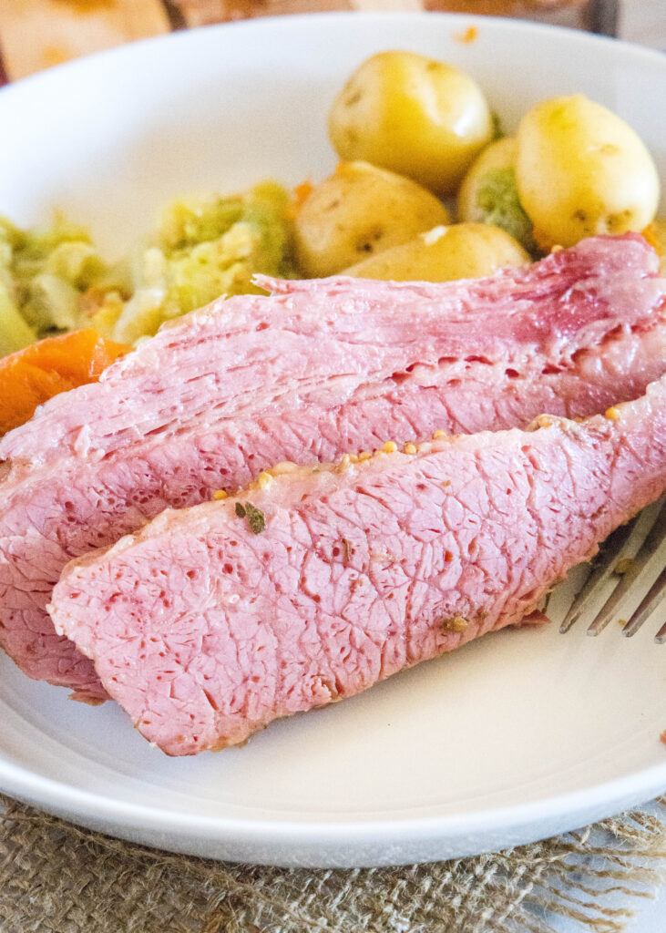 corned beef on a plate with cooked carrots, potatoes and cabbage