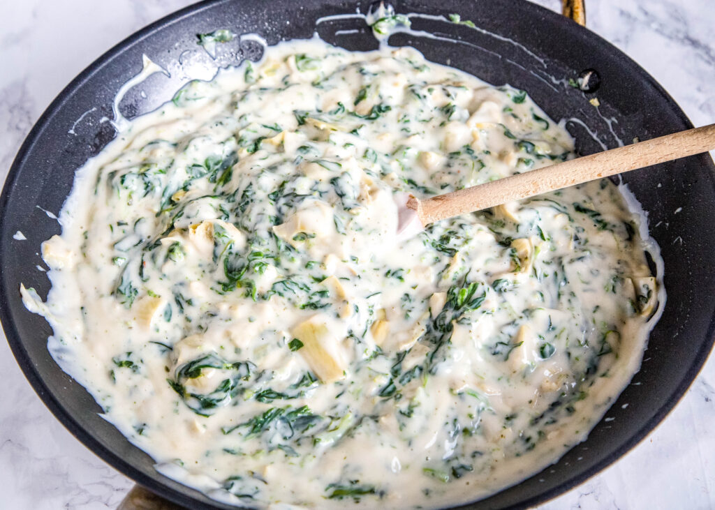 spinach and aritches sauce in a frying pan