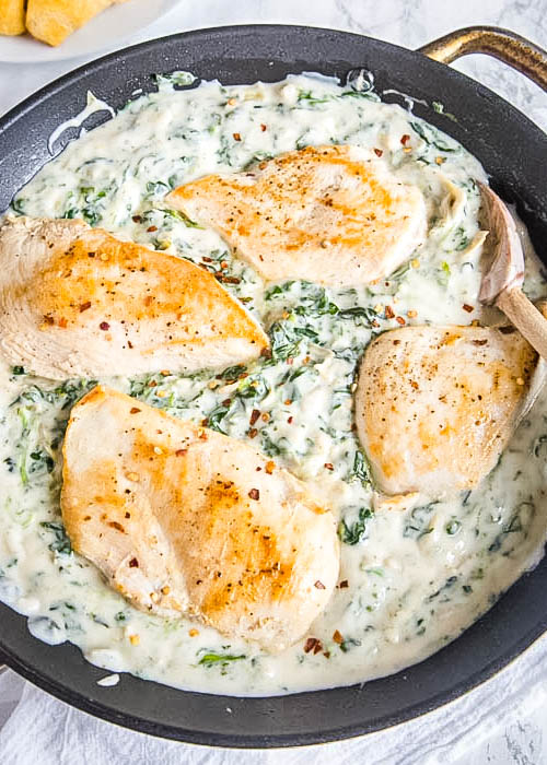 looking down on skillet of chicken with spinach and artichokes