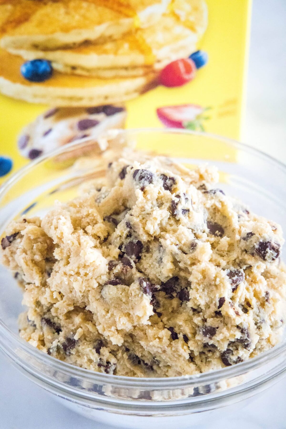 A mixing bowl full of chocolate chip cookie dough in front of a box of Bisquick