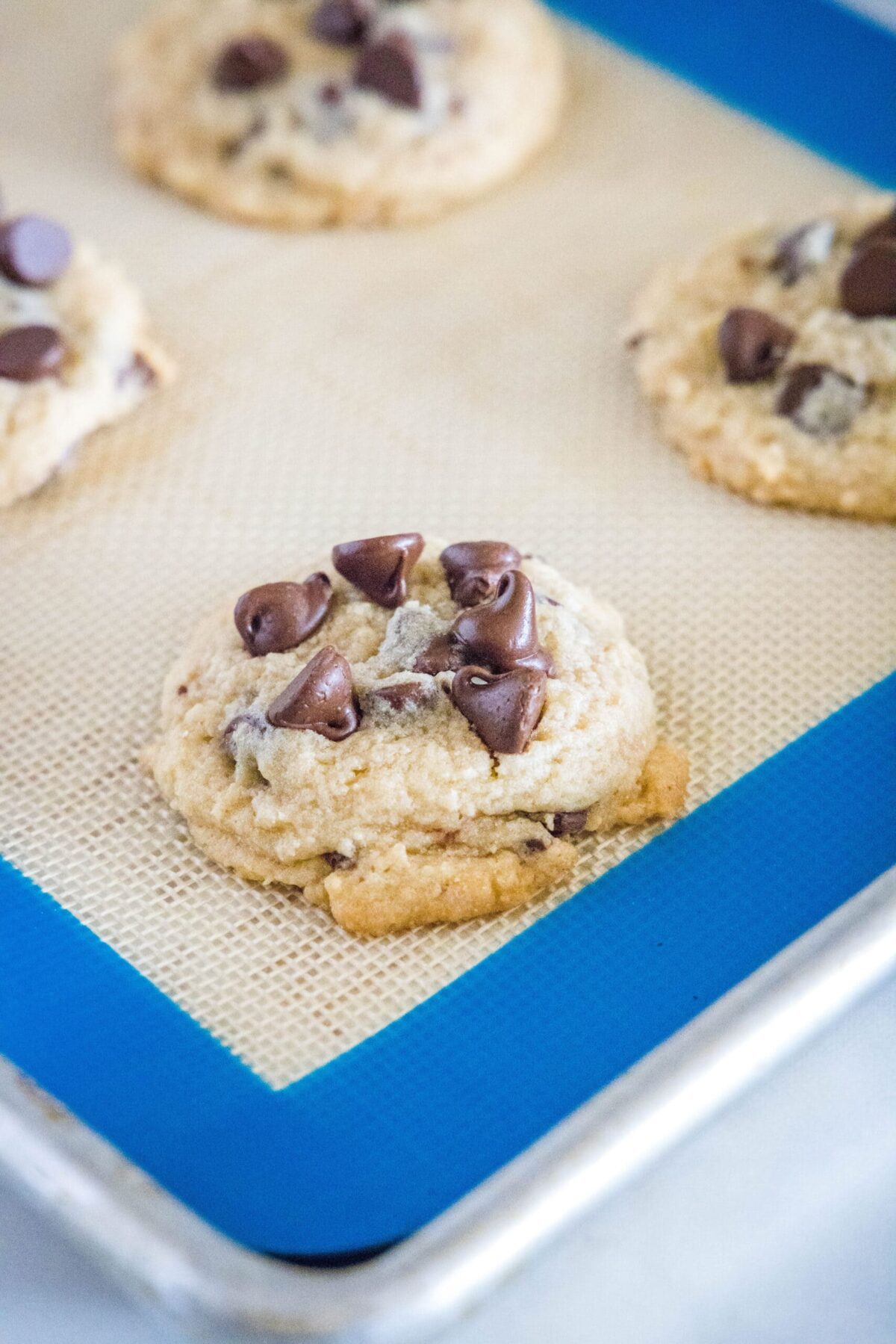 Close up of baked chocolate chip cookies on a silicone mat on a baking sheet