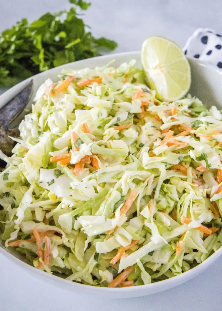 white bowl with coleslaw in a lime wedge