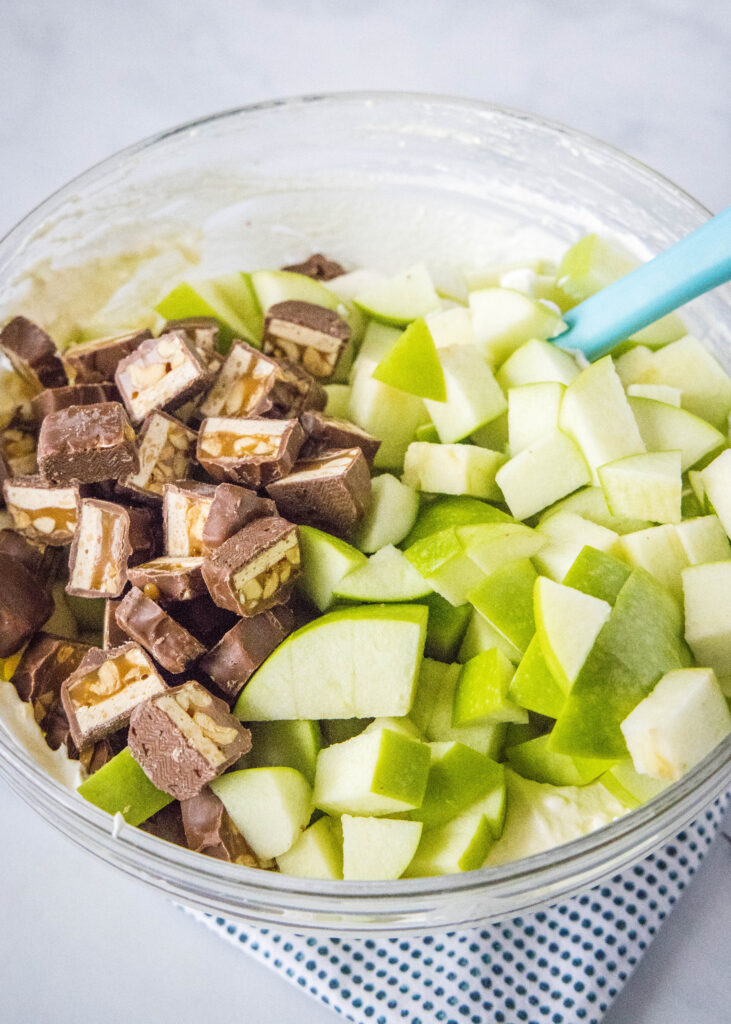 apples and snickers added to a mixing bowl
