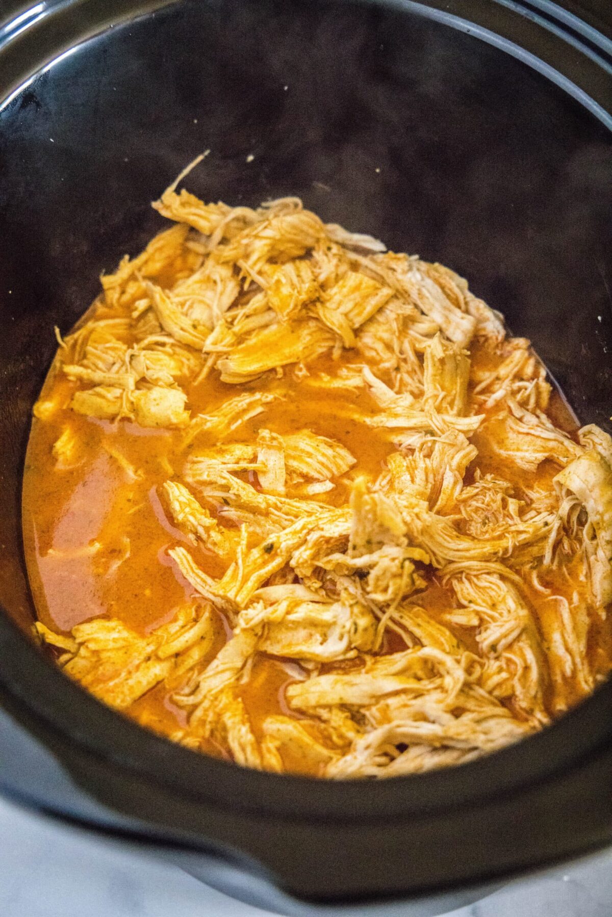 Shredded chicken in a slow cooker with a buffalo sauce