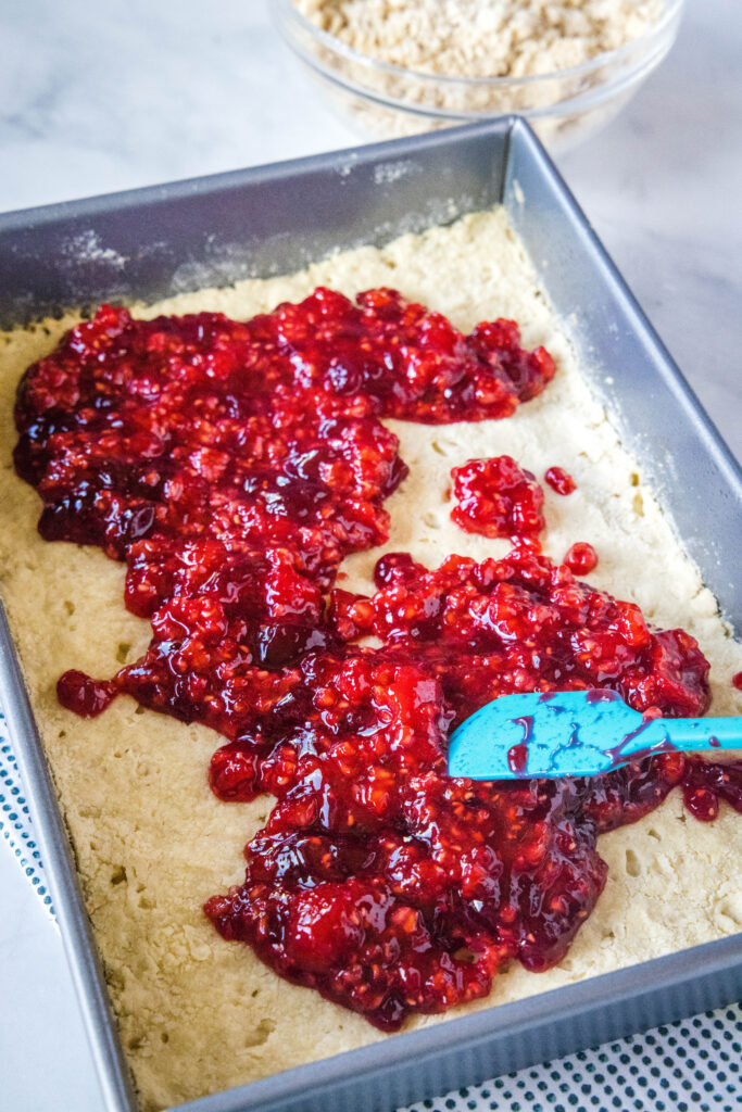 spreading raspberry filling over shortbread crust