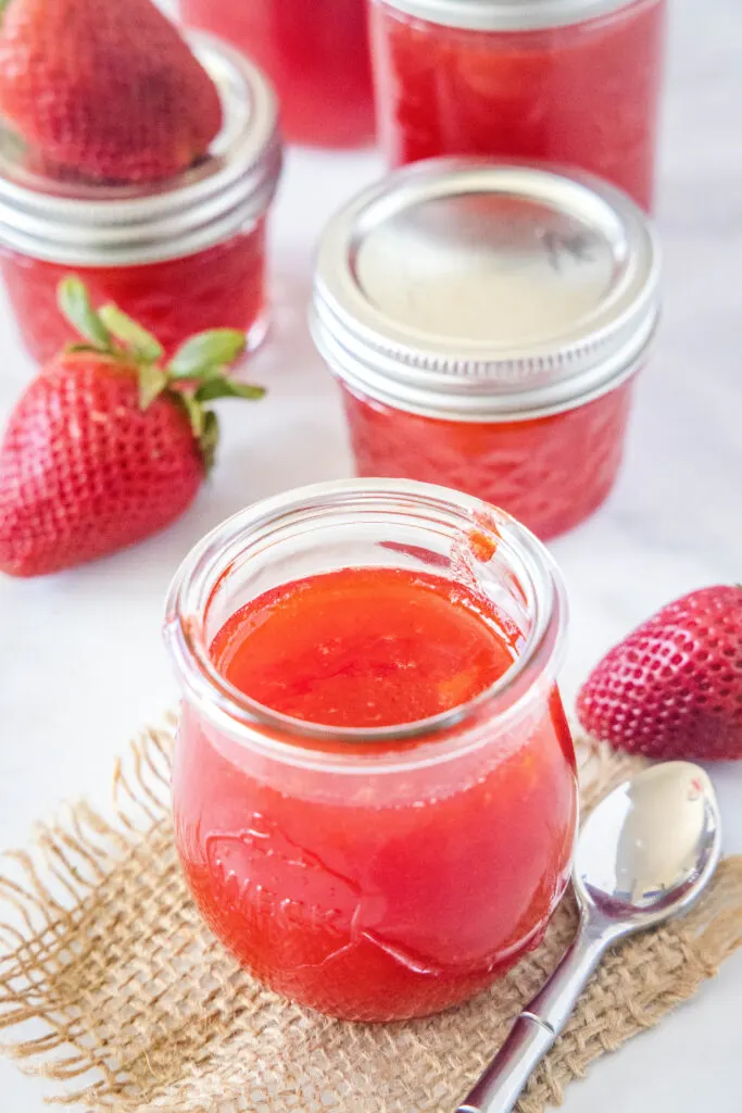jars of strawberry jelly with a spoon next to it