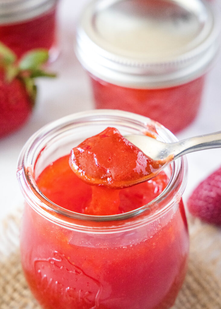 spooning strawberry jelly out of a jar