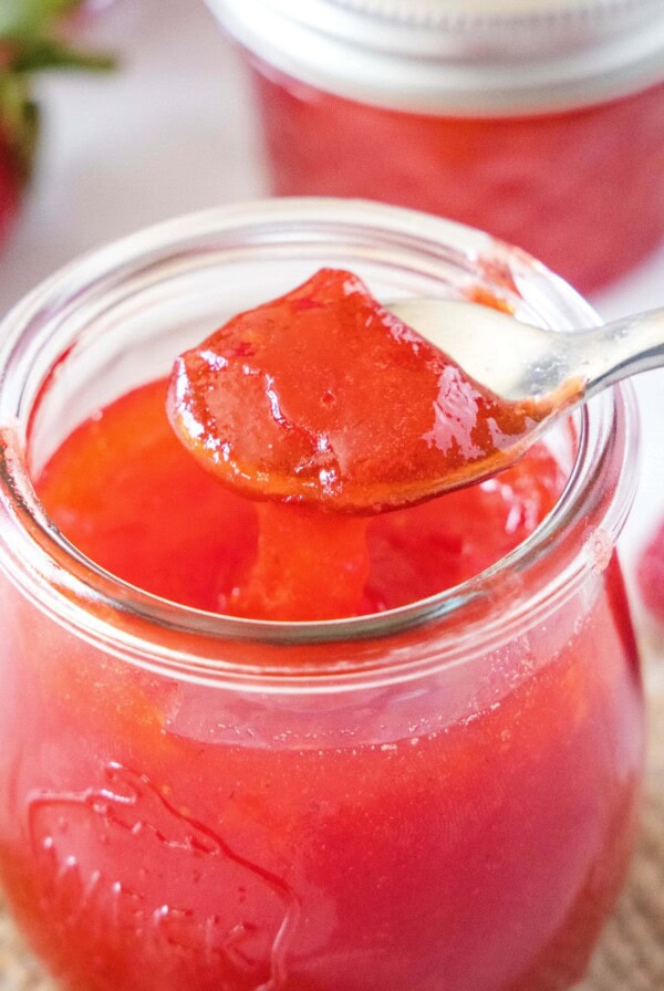 close up of jelly on a spoon over a jar