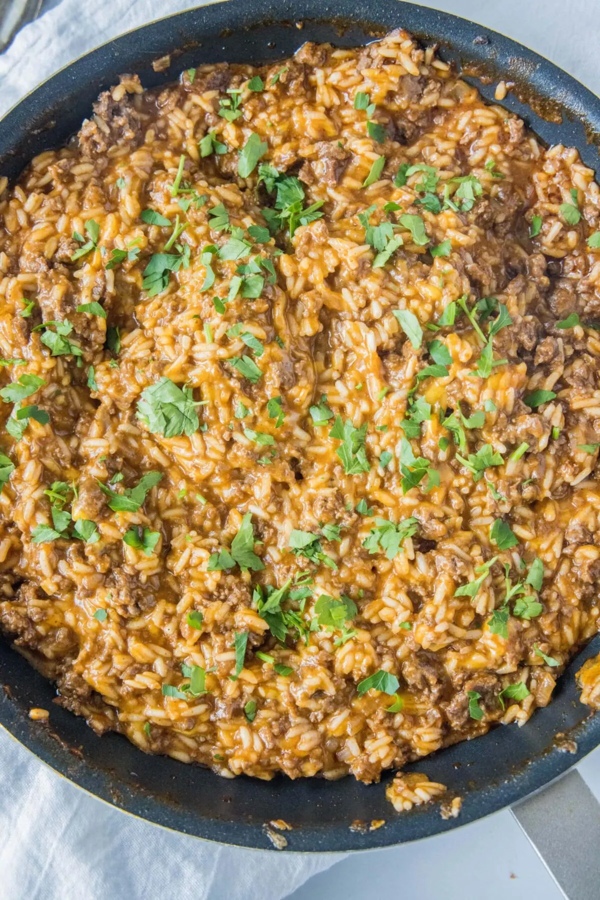 Overhead view of a skillet filled with beefy taco rice, topped with cilantro