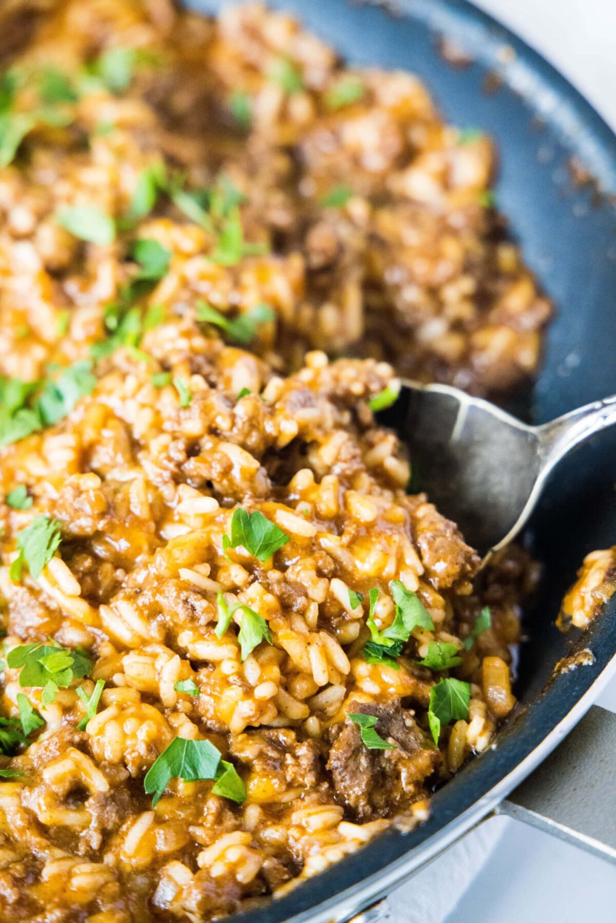 Close up of a spoon taking a spoonful of beefy taco rice out of a skillet