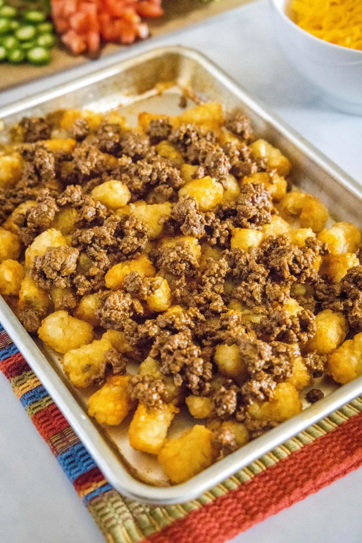 A baking sheet filled with tater tots covered in ground beef