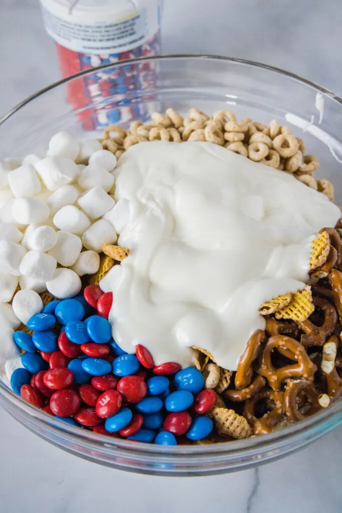 pouring white chocolate over snack mix