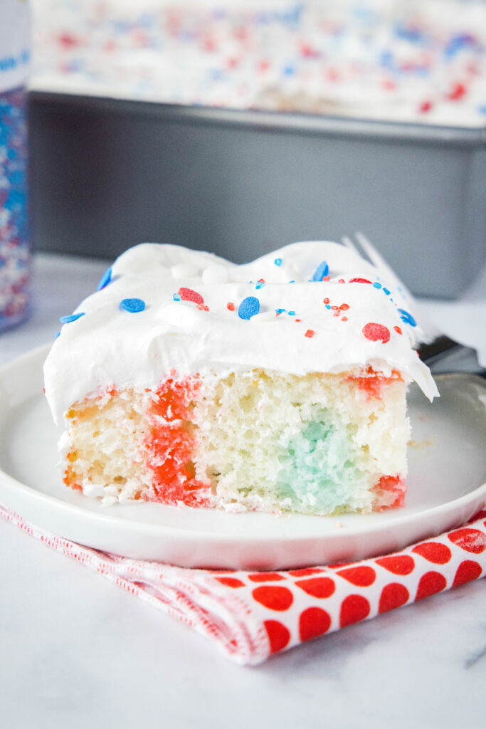 Slice of red, white and blue poke cake on a plate