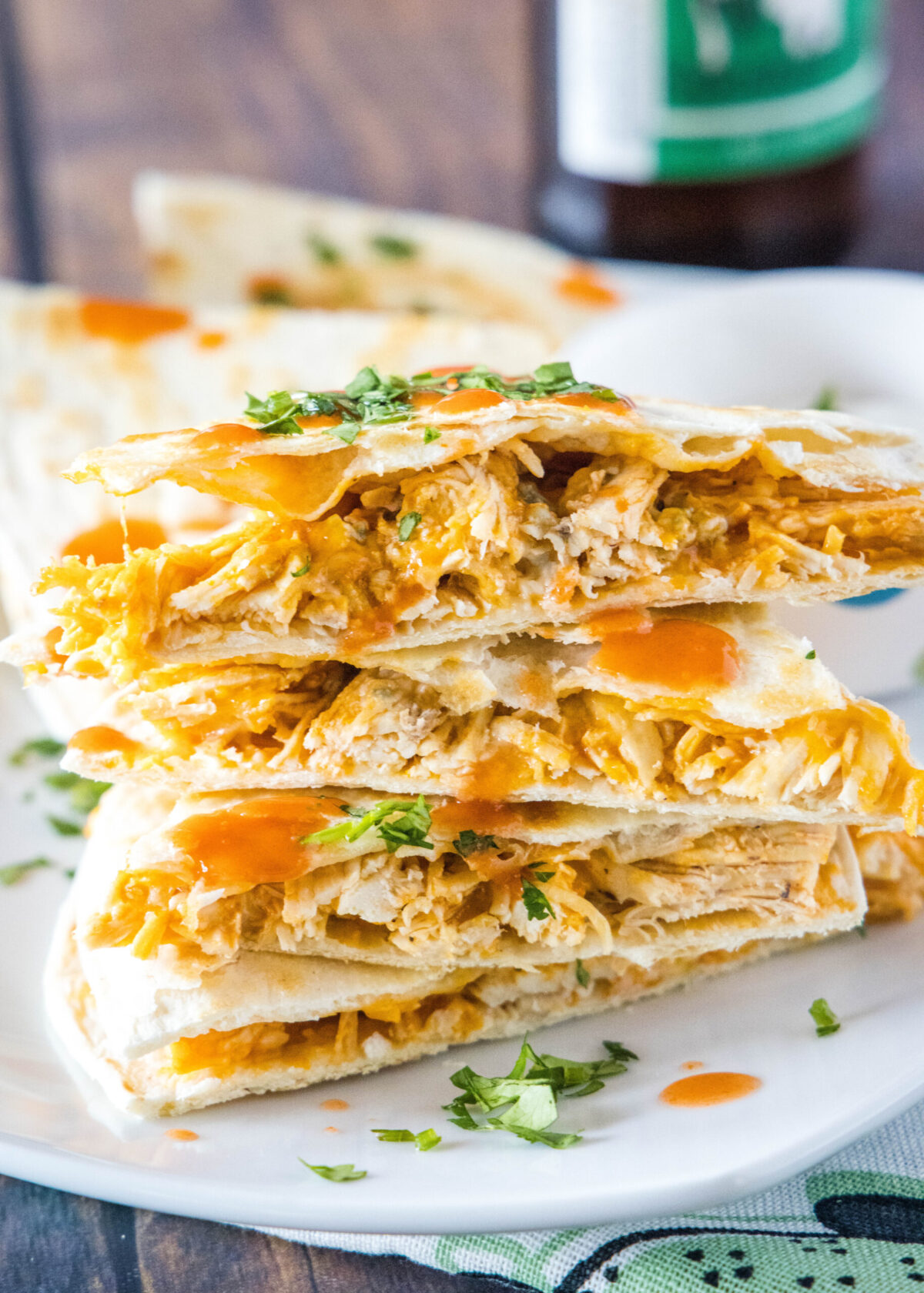 Close up of a stack of buffalo chicken quesadilla triangles, topped with cilantro