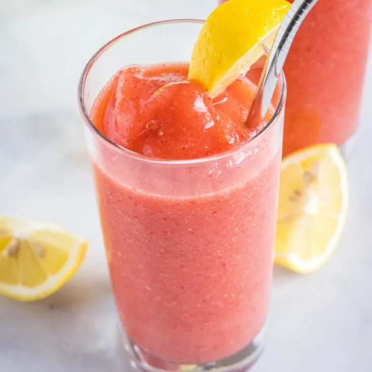 a glass of frozen strawberry lemonade for a slice of lemon
