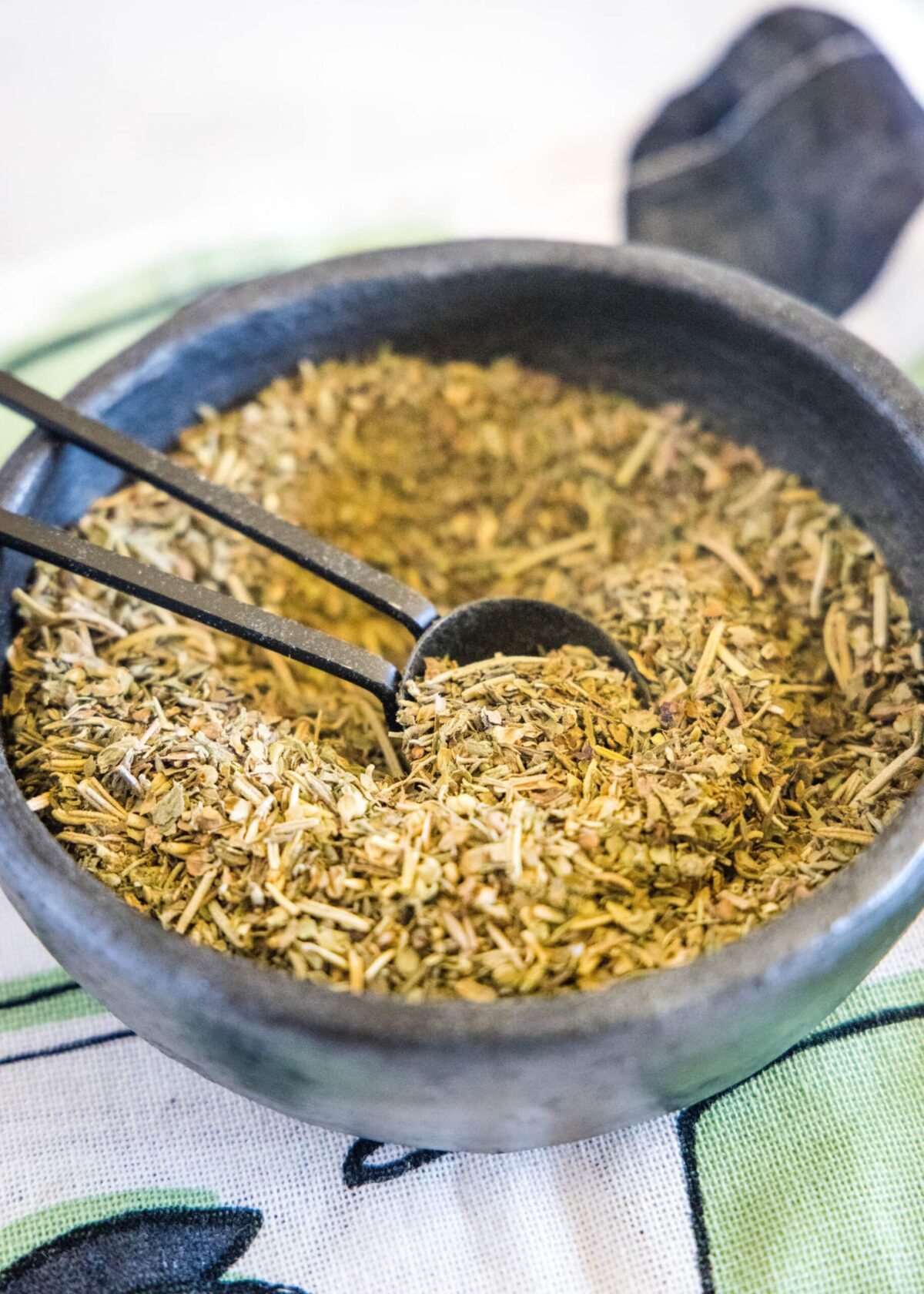 Close up of a bowl of Italian seasoning with a spoon in it