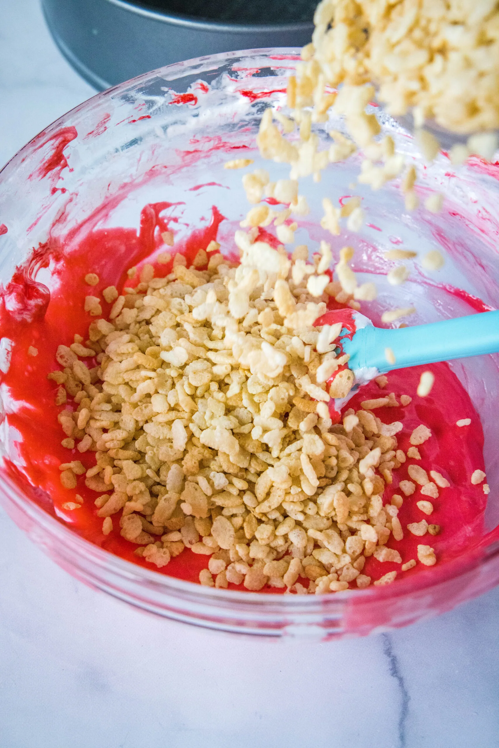 adding krispies to melted red marshmallows