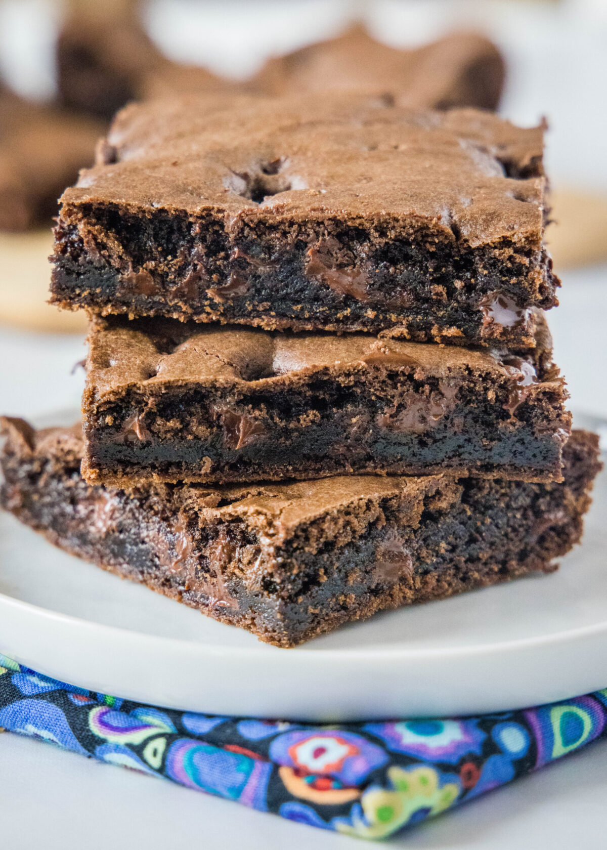 Close up of three brownie squares stacked on top of each other on a plate