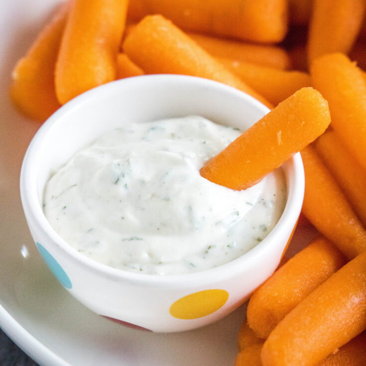 cropped close up dipping a carrot in ranch