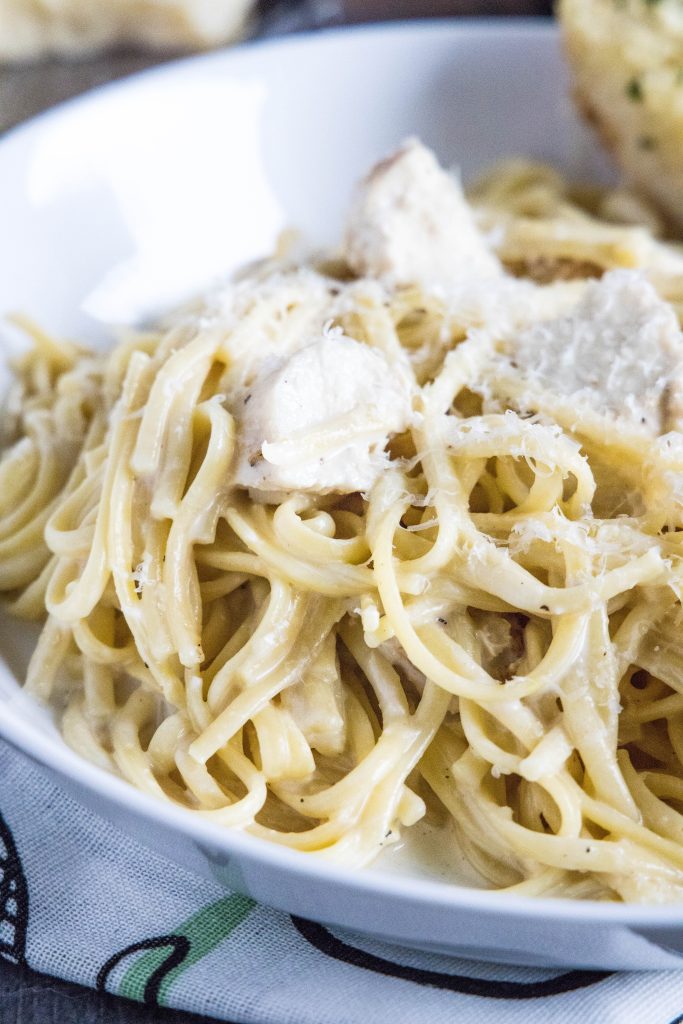 close up of chicken alfredo in a white bowl