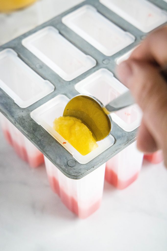 spooning peach puree into popsicle molds