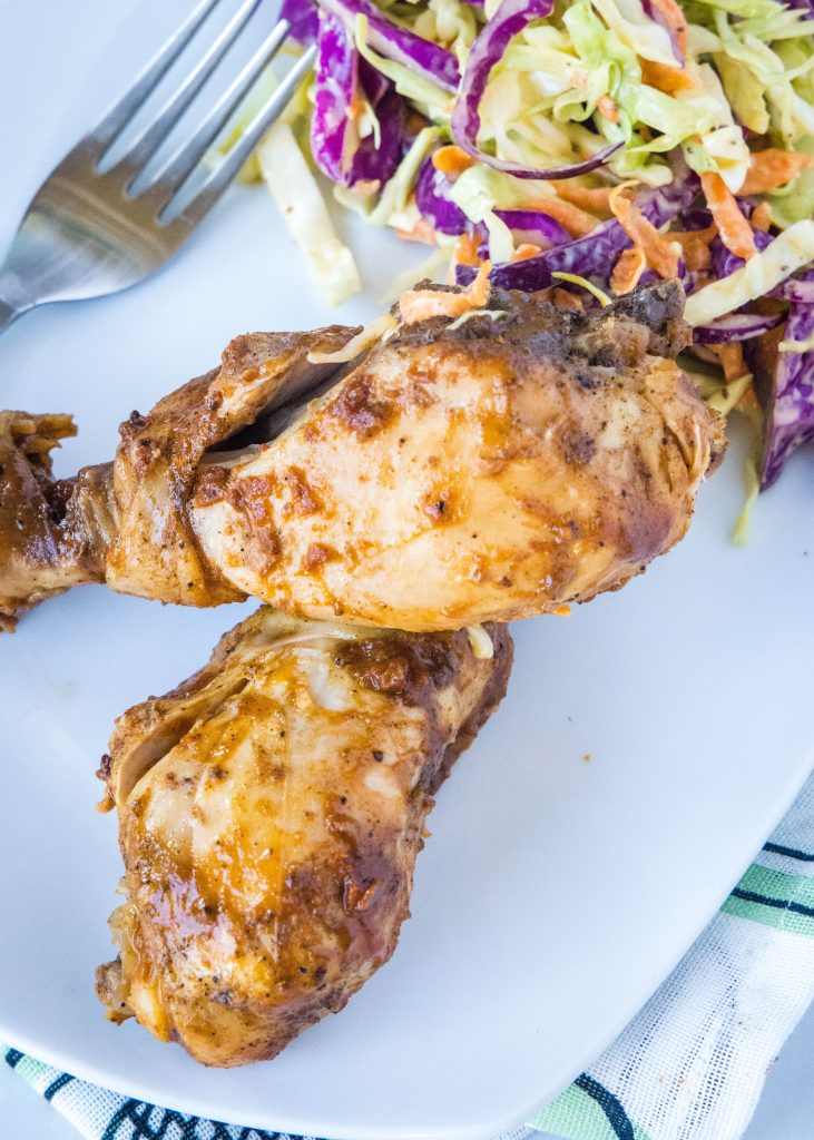 looking down on a white plate with slow cooker chicken drumsticks and coleslaw