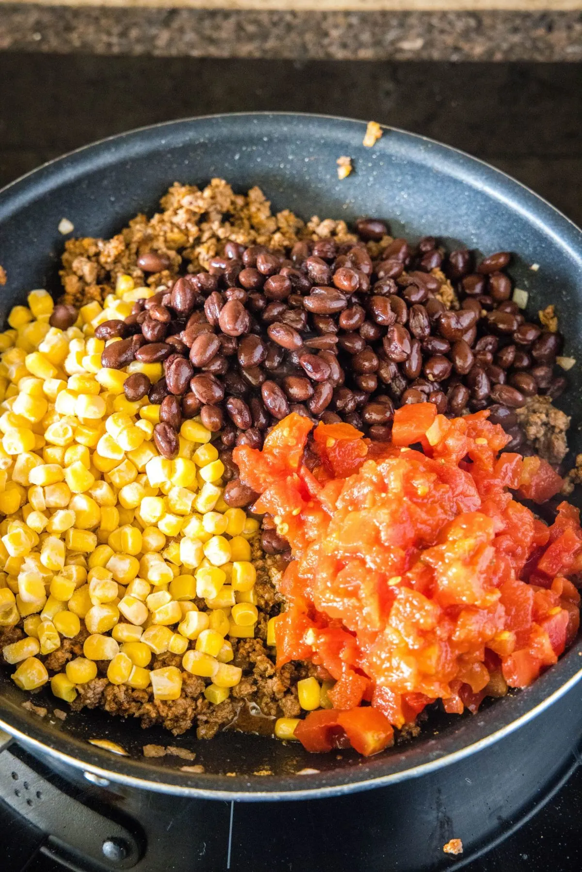 Dieser einfache 30-Minuten-Taco-Auflauf ist vollgepackt mit saftigem und zartem Rindfleisch, klebrigem geschmolzenem Käse und Ihren Lieblings-Taco-Toppings. Mais, schwarze Bohnen und Salsa in einer Pfanne auf Hackfleisch und Zwiebeln geben