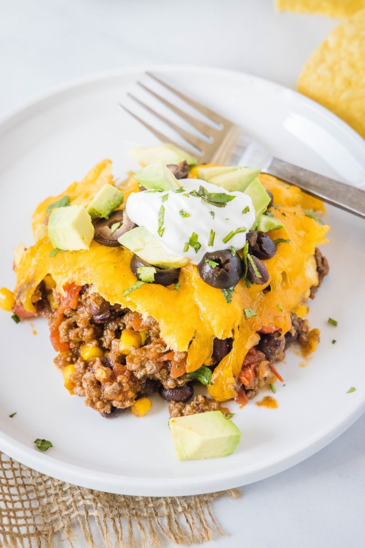 Overhead view of a serving of taco casserole on a plate, with a fork