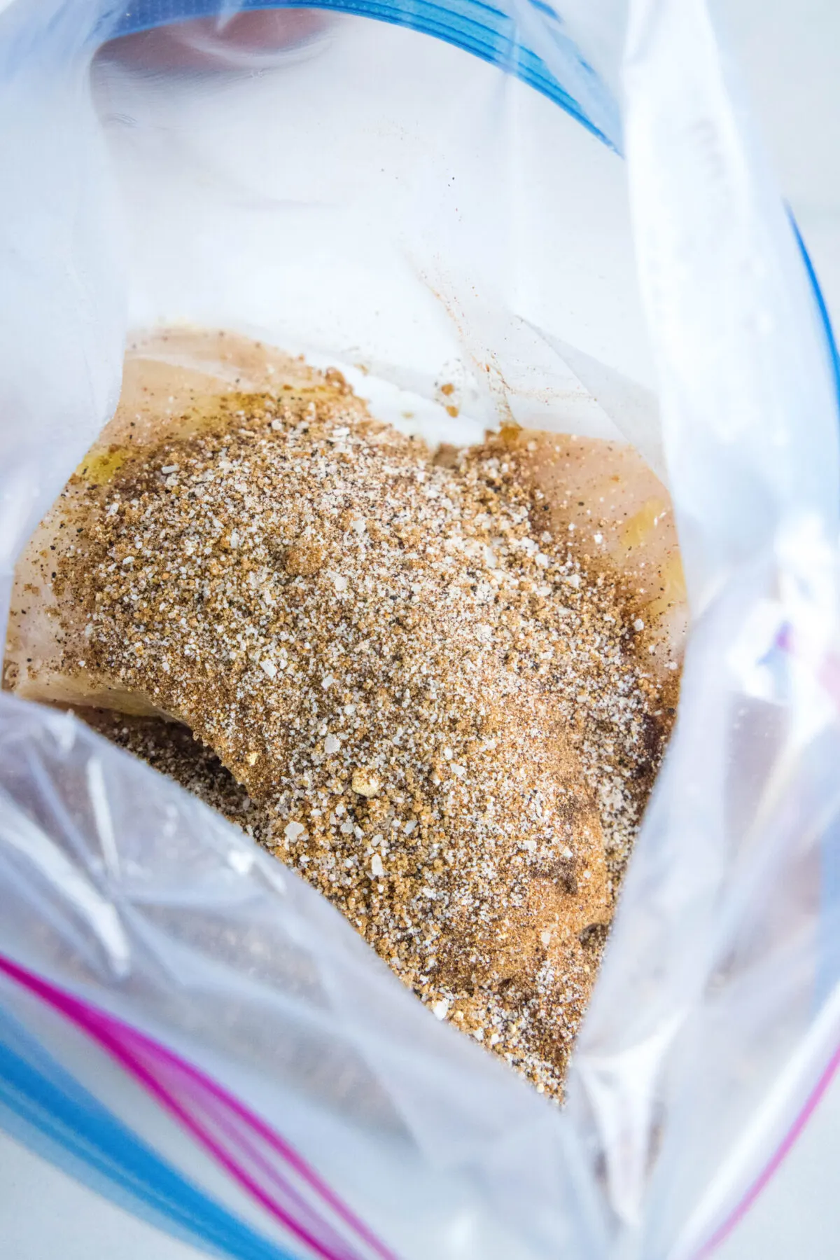 Raw chicken breasts and spice rub in a plastic bag