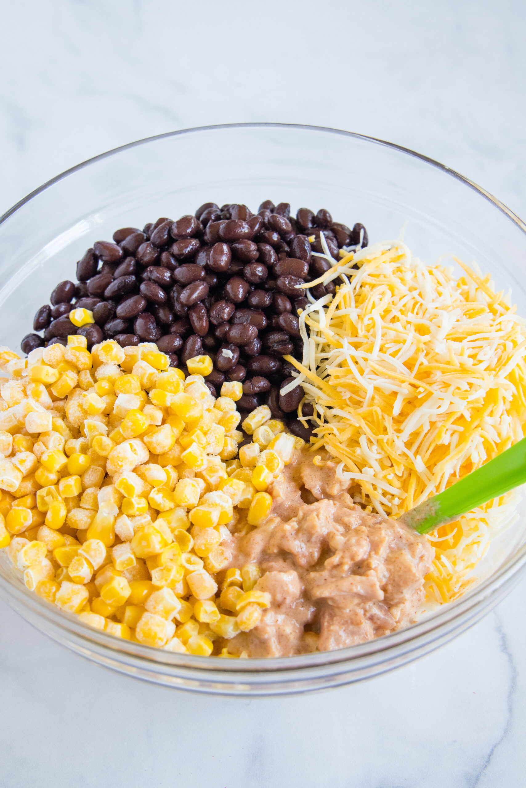 chicken, corn, black beans, and cheese in a mixing bowl