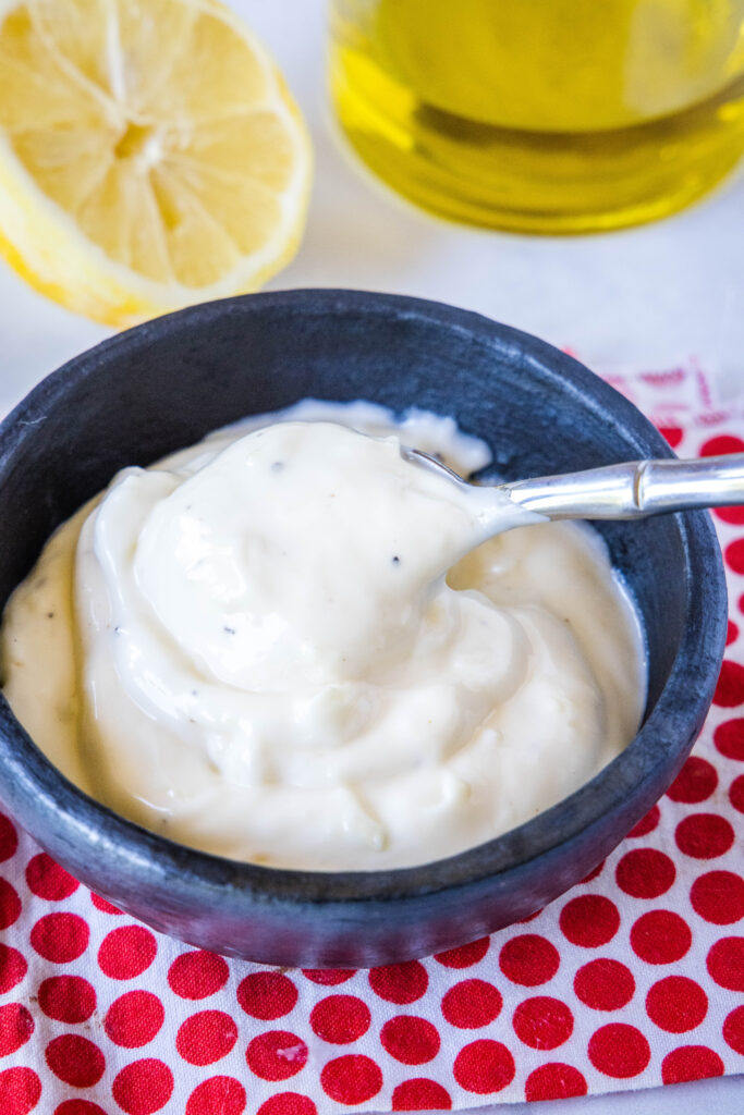 spooning homemade garlic aioli from a bowl