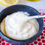 close up spooning garlic aioli from a small bowl