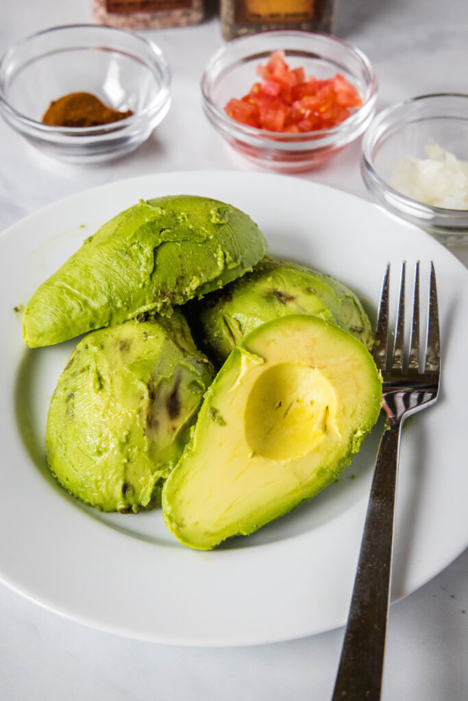 avocados on a plate with a fork ready to mash