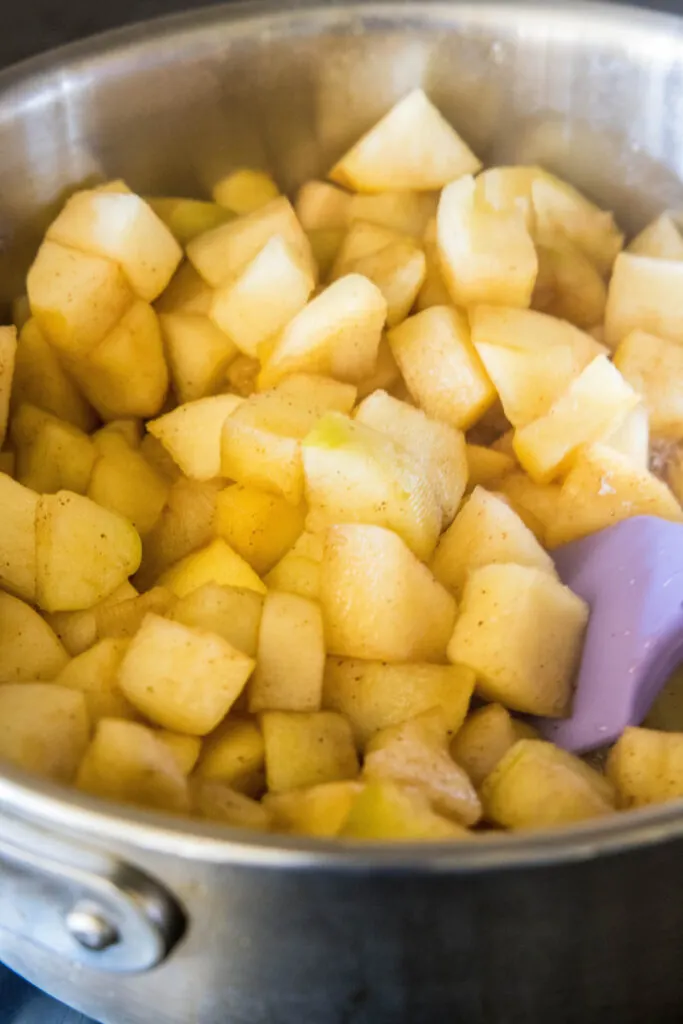 A pot full of apple cubes, with a rubber spatula mixing them