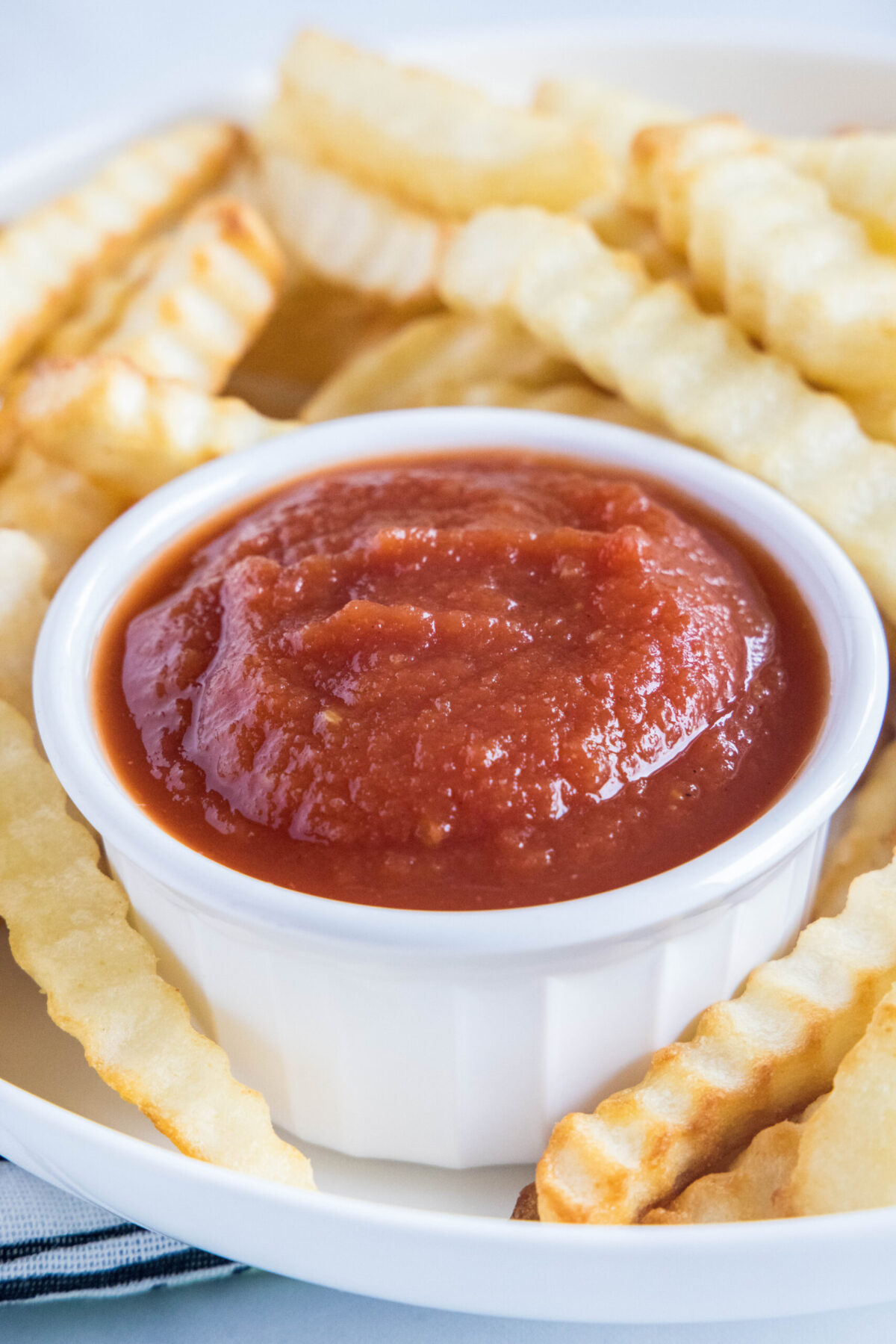 A ramekin of ketchup on a plate of fries