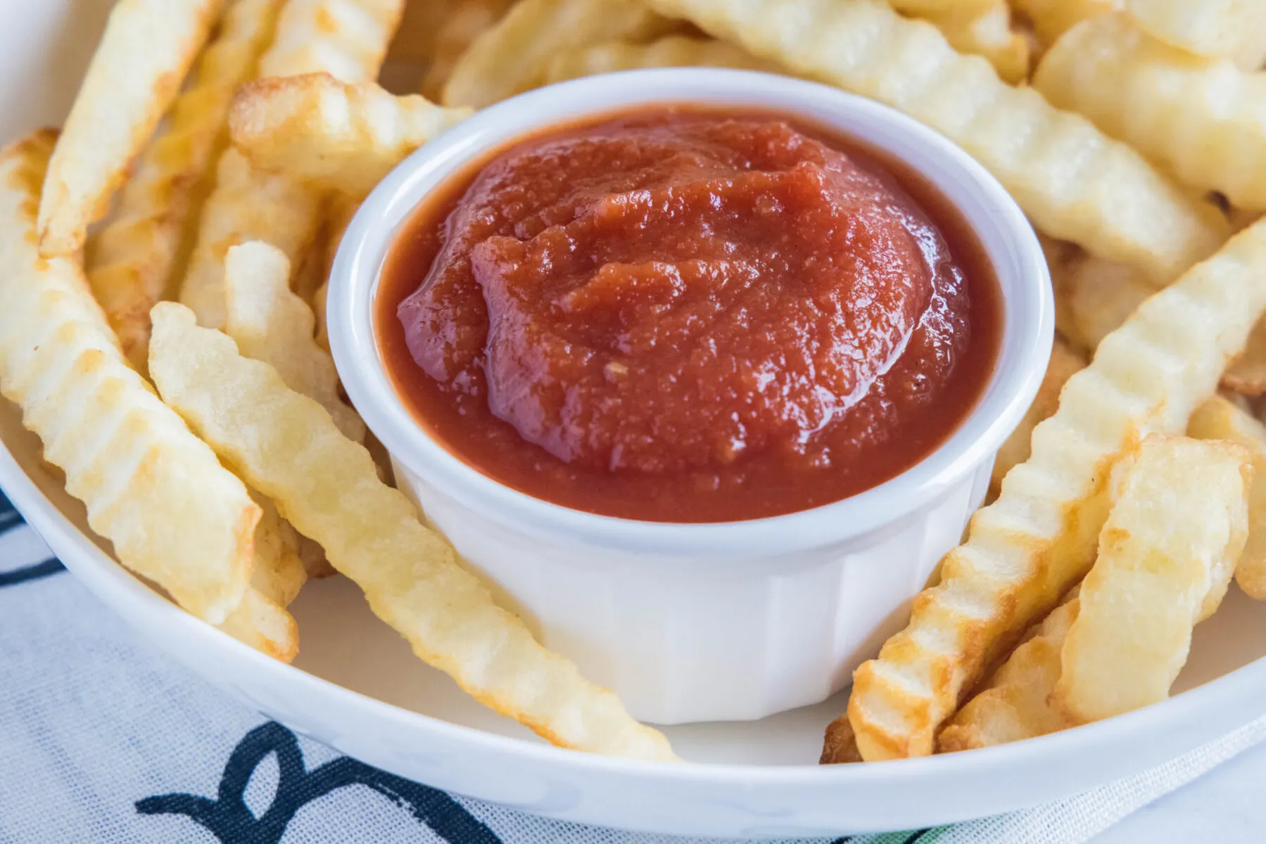 A ramekin of ketchup surrounded by fries