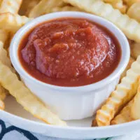 Close up of a ramekin of ketchup surrounded by fries