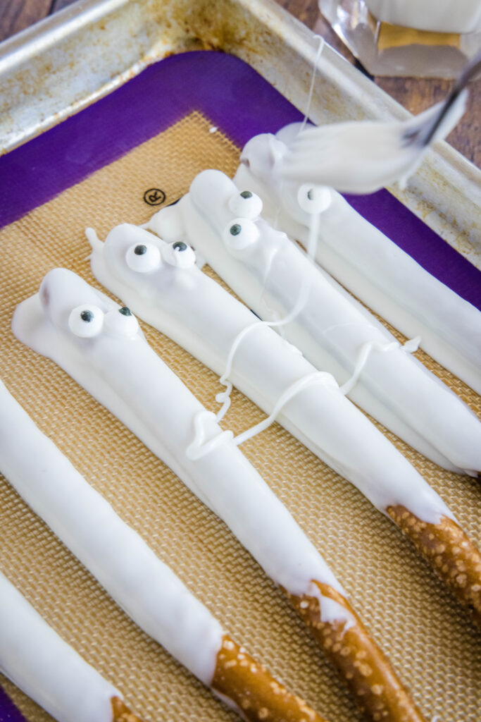 drizzling white chocolate over pretzel rods