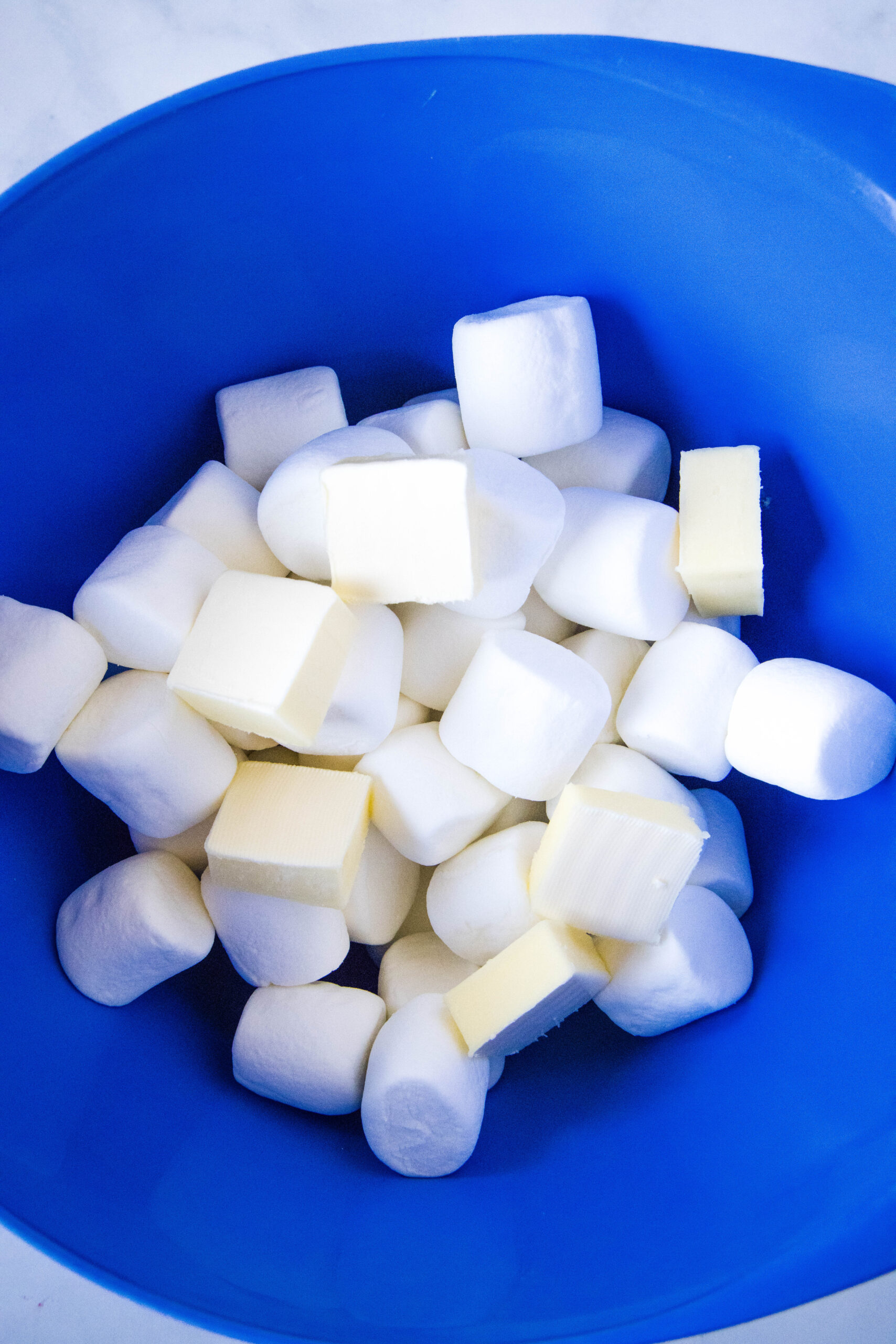 marshmallows and pieces of butter in a mixing bowl