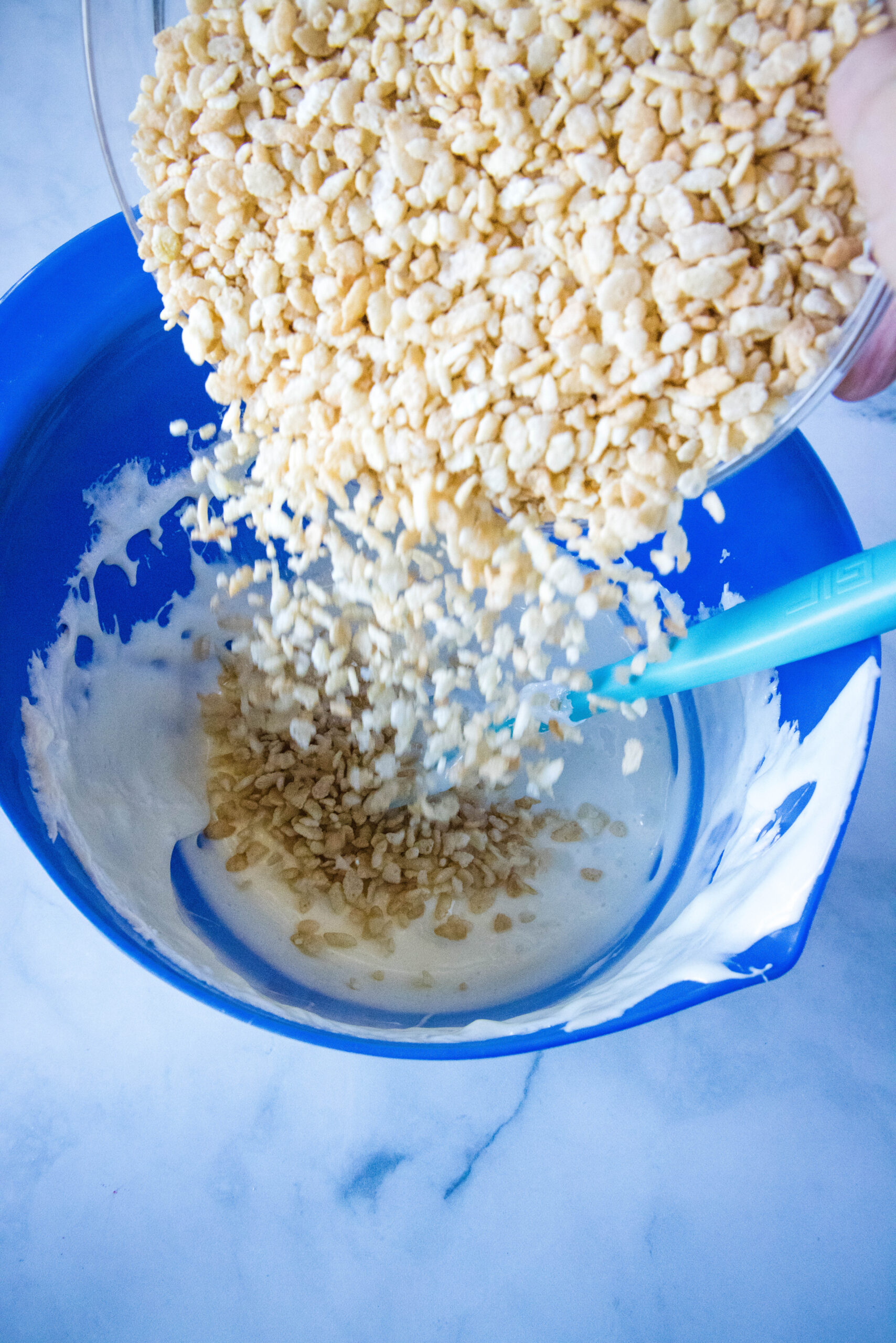 adding rice krispies to melted marshmallows