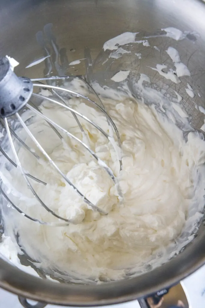 A stand mixer whisk beating stabilized whipped cream in a bowl