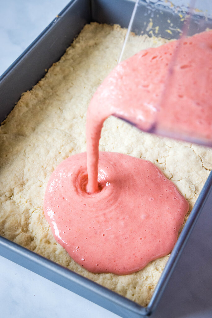 pouring strawberry filling over shortbread crust