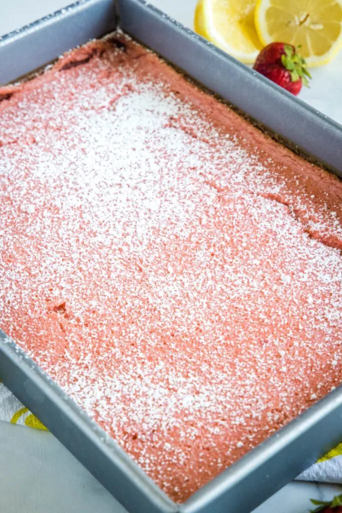 baked strawberry lemon bars with powdered sugar in baking pan